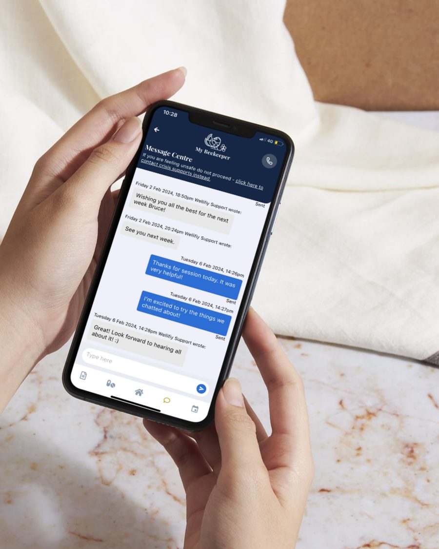 Two hands holding a phone open on the My Beekeeper message centre, a thread between a client and their support team