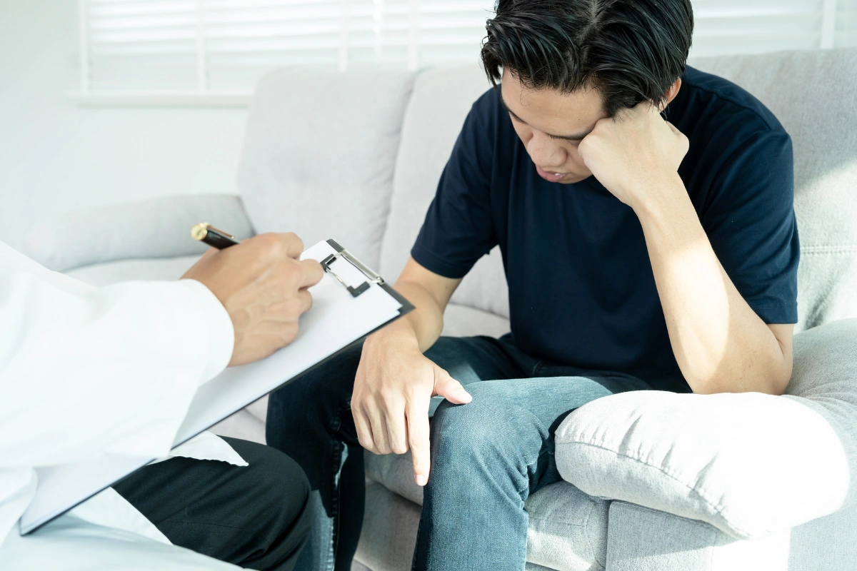 Man talking to a clinician taking notes during a medical assessment