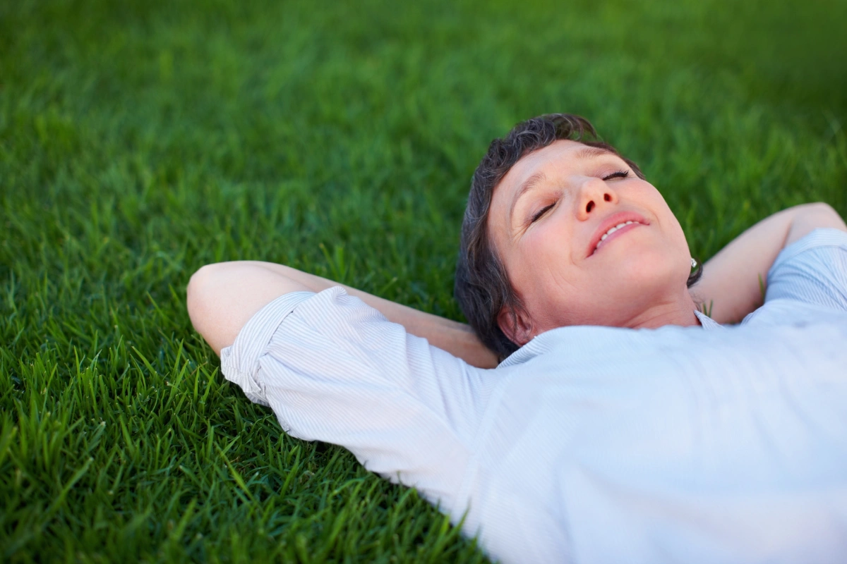 Woman lying on the grass with eyes closed, relaxed and at peace