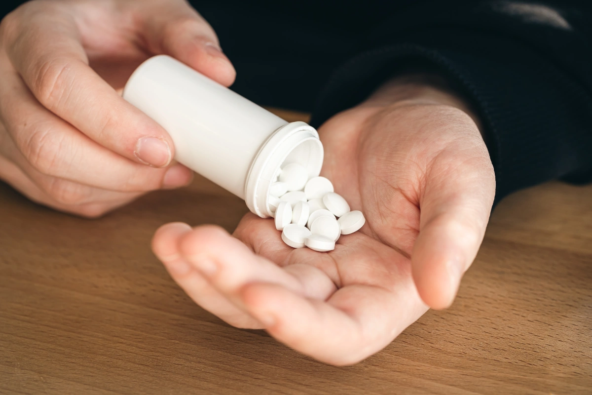 Person holding a handful of prescription pills, illustrating temazepam addiction and benzodiazepine dependence.