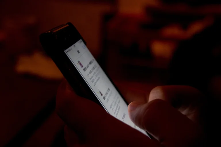 Person using a smartphone late at night, illustrating compulsive behaviour patterns treated in Thailand