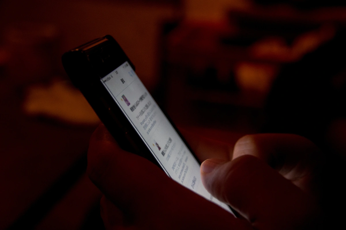 Person using a smartphone late at night, illustrating compulsive behaviour patterns treated in Thailand