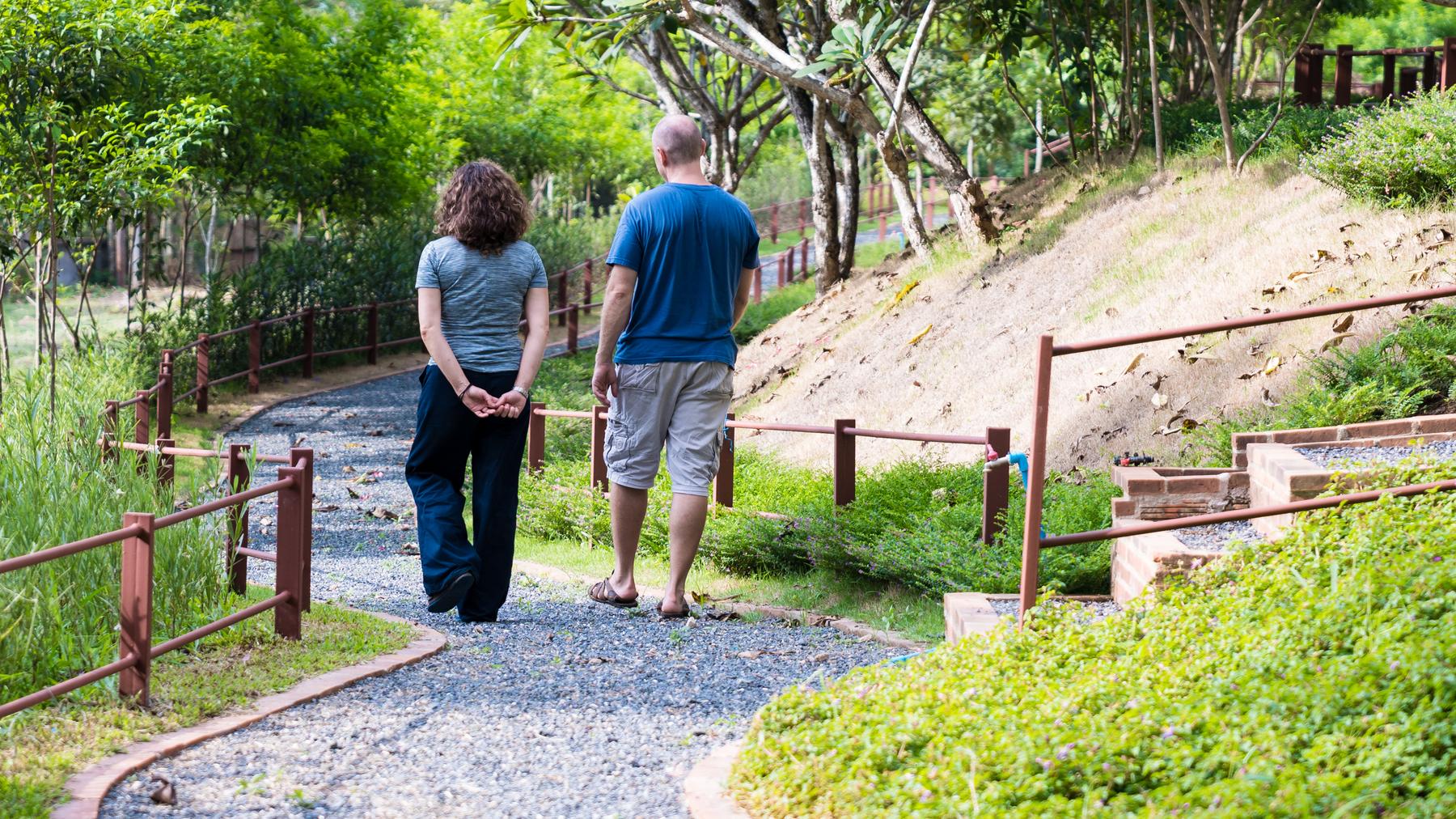 Two people walking together along a gravel path through the grounds