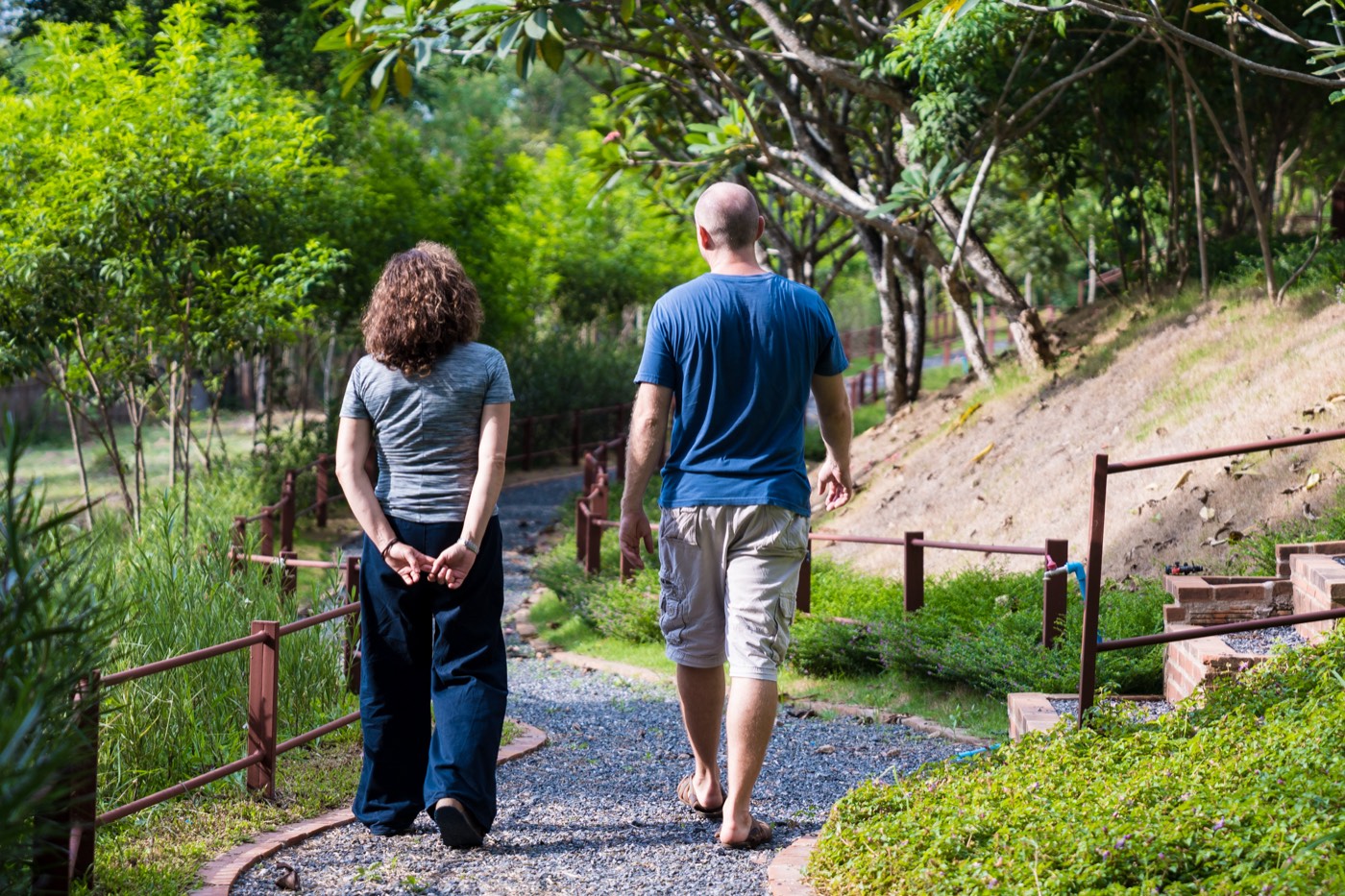 Two people walking away along a gravel path through the planted grounds