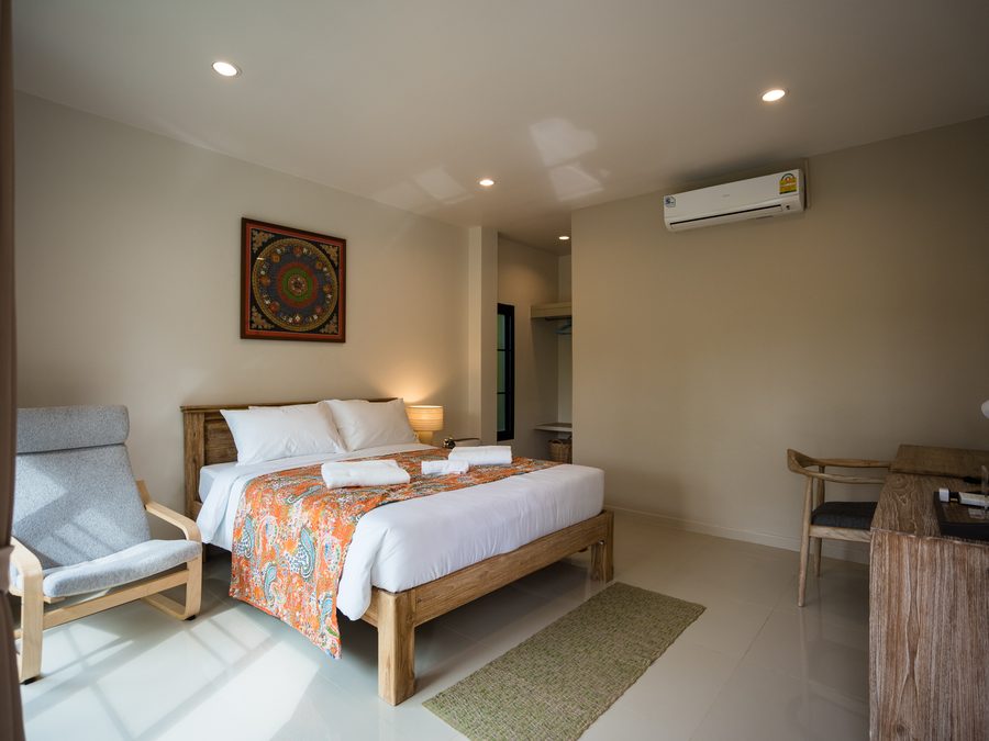 A private bedroom, made up, with a chair by the window