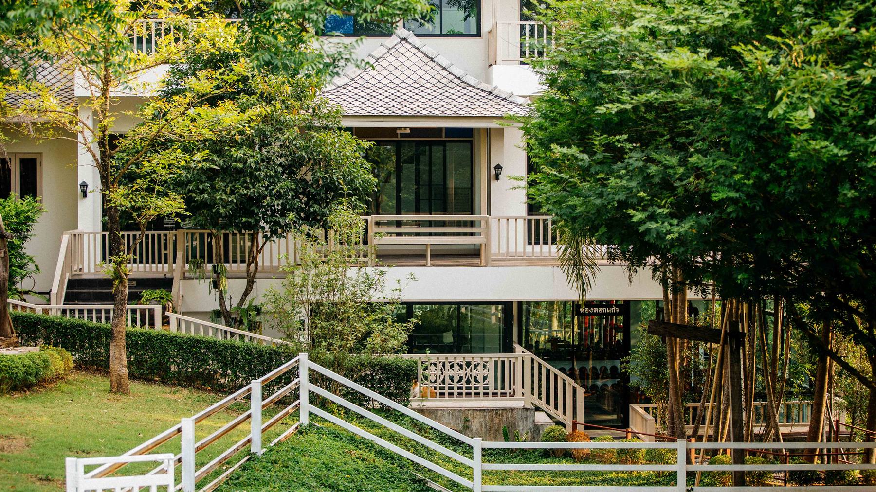 The residential villa seen across the lawn, its balconies set among trees
