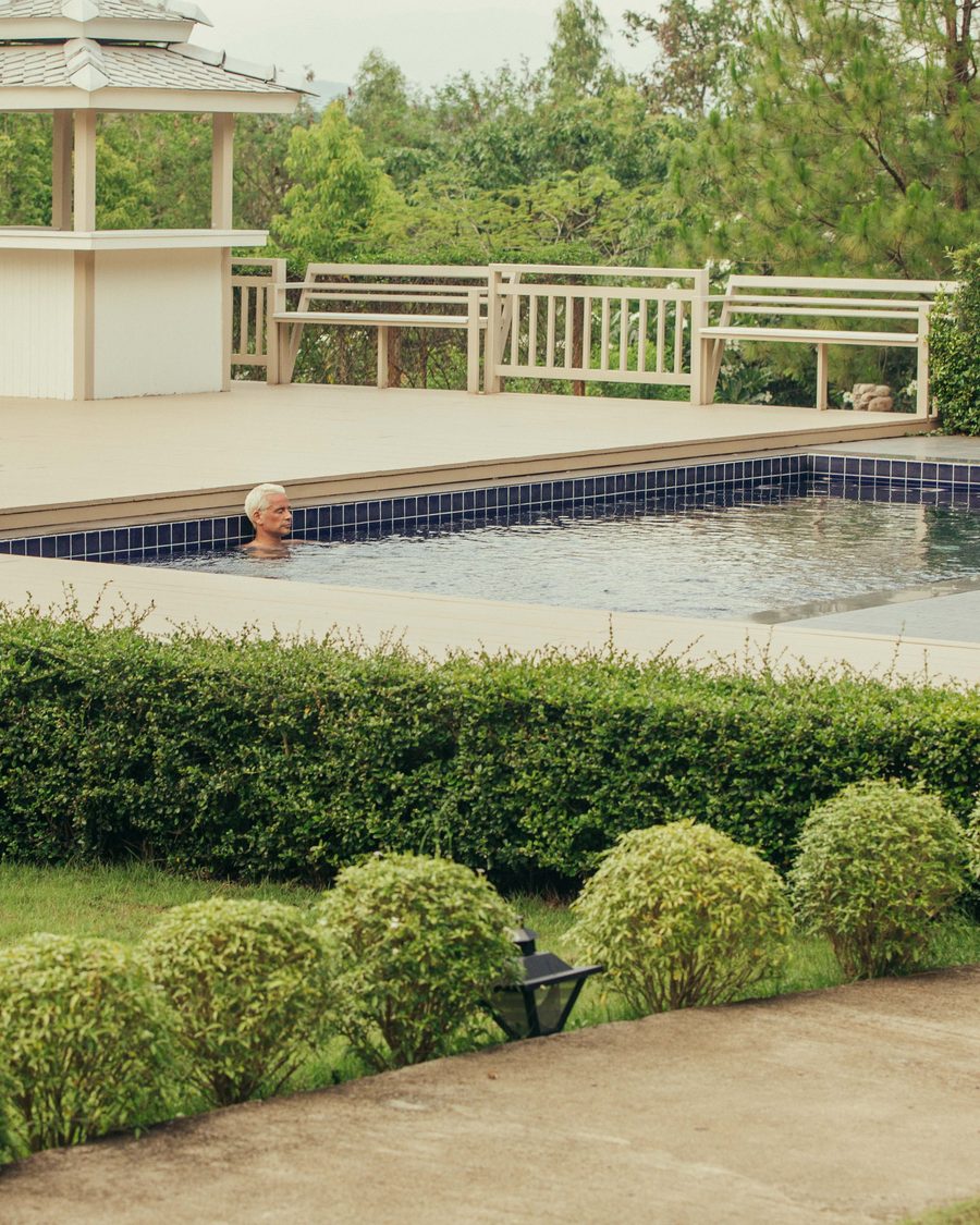 The pool, seen across clipped hedges in the grounds